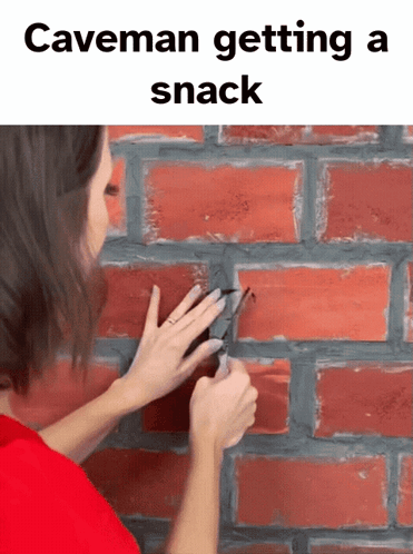 Woman Cutting Hole In Brick Wall With Scissors Caveman Getting A Snack GIF
