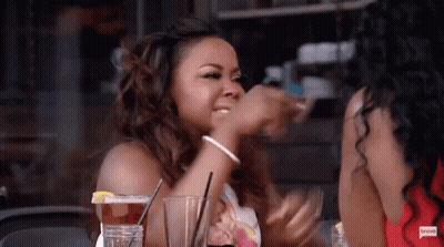 Woman Drinking At Table Beside Another Woman GIF