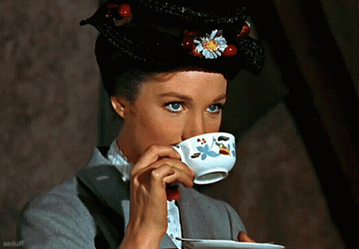 Woman Drinking From Cup With Flower On Hat GIF