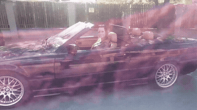 Woman Driving Black Convertible With Purple Smoke GIF