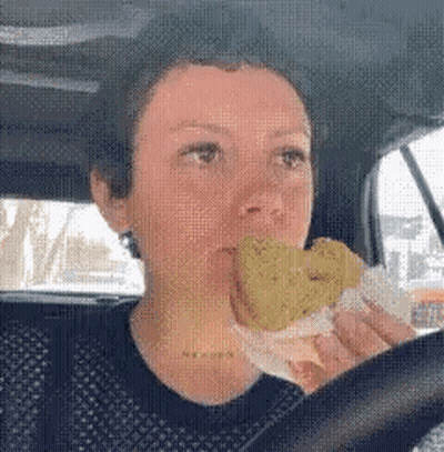 Woman Driving Car Eating Fried Sandwich