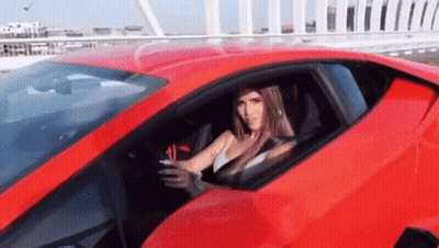 Woman Driving Red Sports Car Looking Out Window GIF