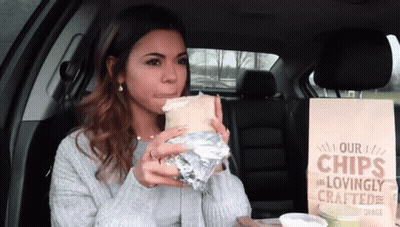 Woman Eating Burrito Next To Chips Bag GIF