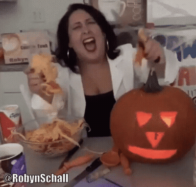 Woman Eating Chips Next To Carved Pumpkin GIF