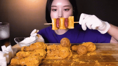 Woman Eating Fried Chicken And Sausage Skewer GIF