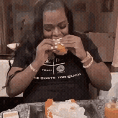 Woman Eating Hamburger And Cake At Table GIF