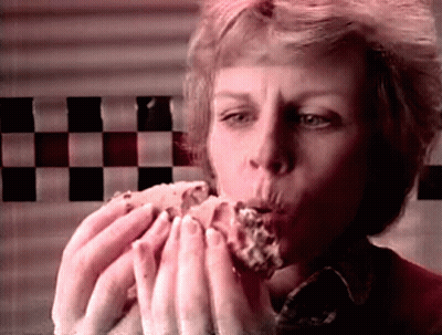 Woman Eating Hamburger In Front Of Checkerboard Wall GIF