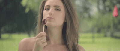 Woman Eating Lollipop In Park GIF