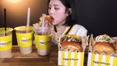 Woman Eating Sandwich Drinking From Eggcellent Cup GIF