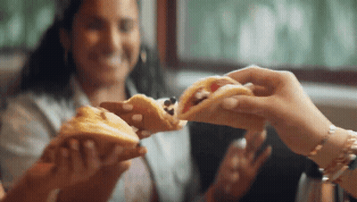 Woman Eating Sandwich While Another Holds One GIF