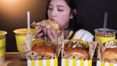 Woman Eating Sandwich With Ingredients On Wrapper GIF
