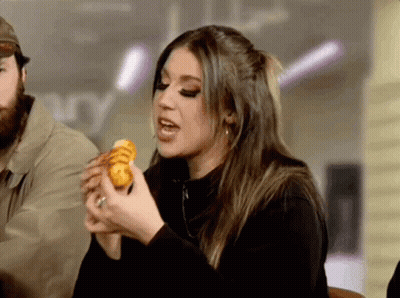 Woman Eating Sandwich With Man Behind Her