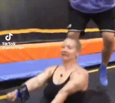 Woman Exercising On Trampoline With Man Behind GIF
