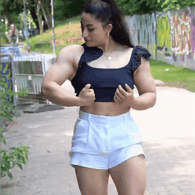 Woman Flexing Muscles In Front Of Graffiti Wall GIF
