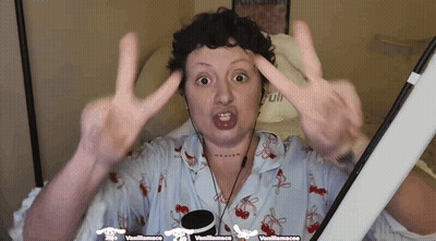 Woman Giving Peace Sign In Front Of Vanillamacaco Sign GIF