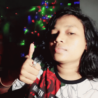 Woman Giving Thumbs Up in Front of Christmas Tree