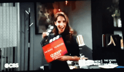 Woman Holding 12,000Th Episode Clapper Board GIF