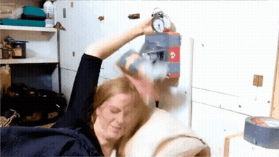 Woman Holding Alarm Clock In Bed GIF
