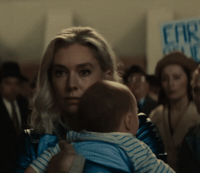Woman Holding Baby in Front of Far Right Sign