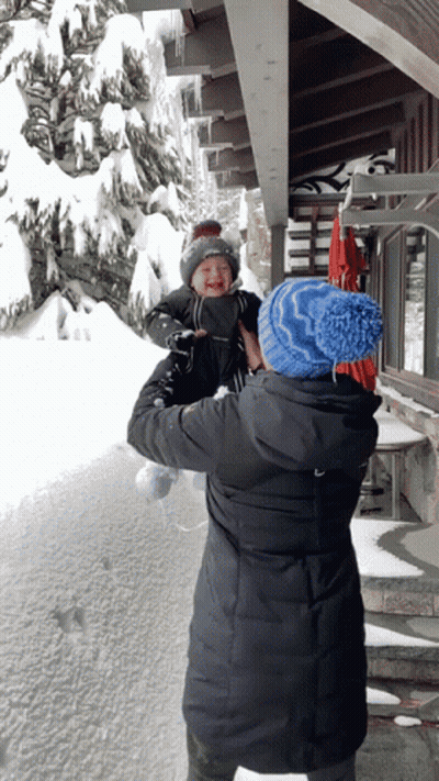 Woman Holding Baby in Front of Snowy Building