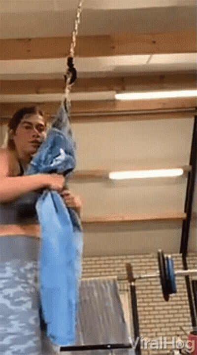 Woman Holding Blue Towel Hanging From Chain In Gym GIF