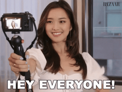 Woman Holding Camera Saying Hey Everyone