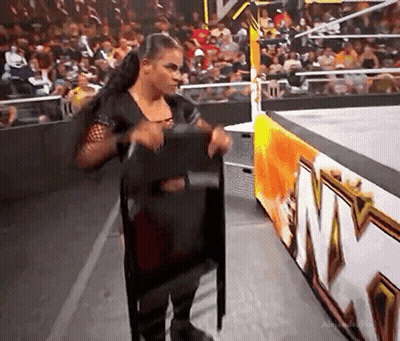 Woman Holding Chair On Stage Before Crowd GIF