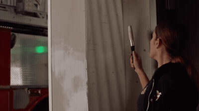 Woman Holding Flashlight In Front Of Wall GIF