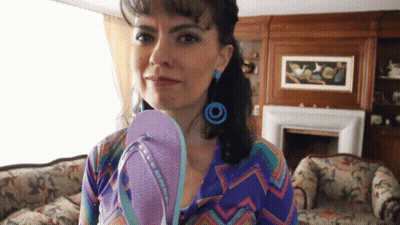 Woman Holding Flip Flops In Front Of Fireplace GIF