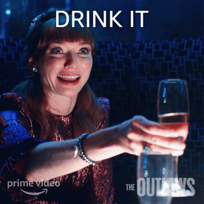 Woman Holding Glass Of Wine In Front Of Drink It Sign GIF
