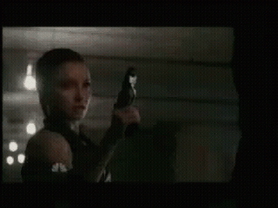 Woman Holding Gun Pointing At Man In Dark Room GIF