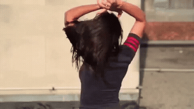 Woman Holding Her Hair In Front Of Building GIF