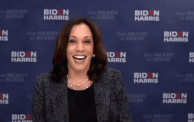 Woman Holding Leg In Front Of Biden Harris Banner GIF