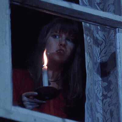 Woman Holding Lit Candle At Night Window GIF