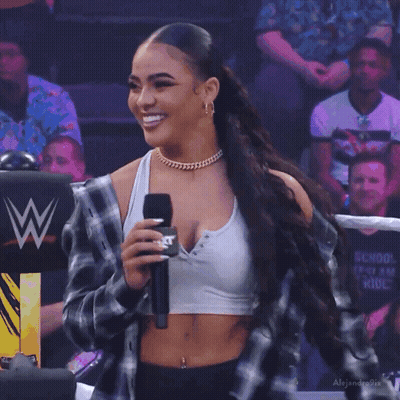 Woman Holding Microphone Before Crowd In Crop Top And Plaid Jacket GIF