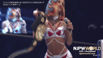 Woman Holding Microphone In Front Of NJPW World Sign GIF