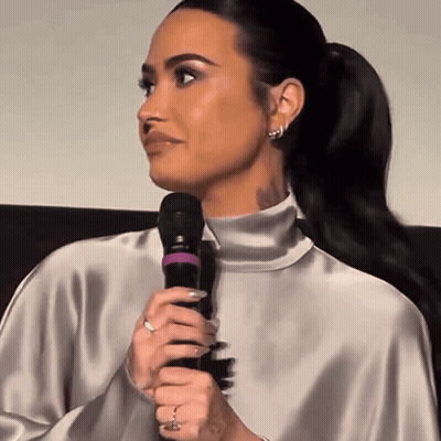 Woman Holding Microphone In Silver Top GIF