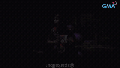 Woman Holding Nerf Gun In Front Of Purple Balloons With GMA Background GIF