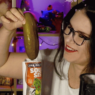 Woman Holding Pickle In Front Of Van Hol Bag GIF