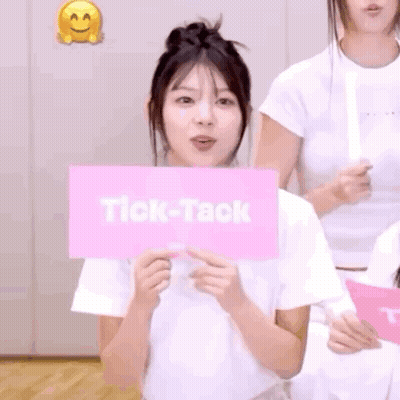 Woman Holding Pink Tick-Tack Sign Behind Face GIF