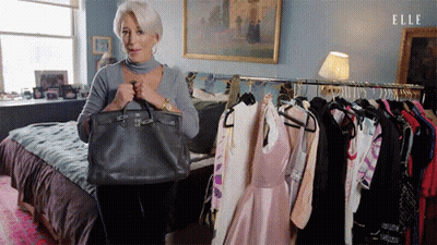 Woman Holding Purse In Front Of Clothes Rack GIF