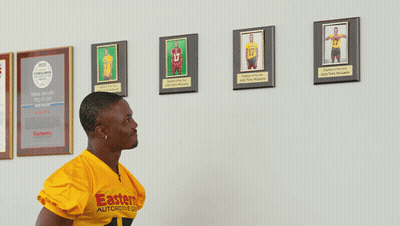 Woman Holding Shirt With Man's Picture While Basketball Player Sits GIF
