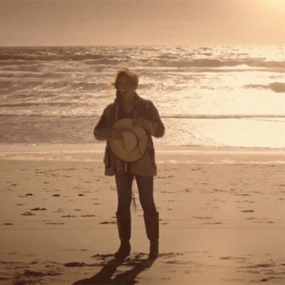 Woman Holding Straw Hat On Beach GIF