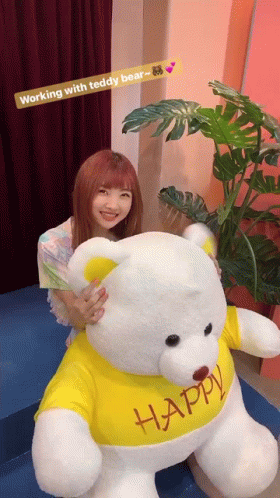Woman Holding Teddy Bear In Yellow Shirt Saying Happy GIF
