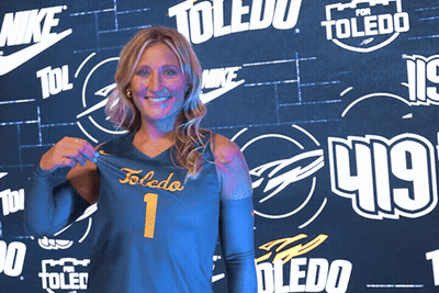 Woman Holding Toledo Jersey In Front Of Nike Wall GIF
