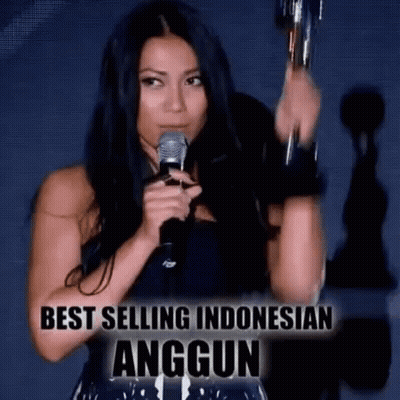 Woman Holding Trophy And Microphone In Front Of Best Selling Indonesian Anggun Sign GIF