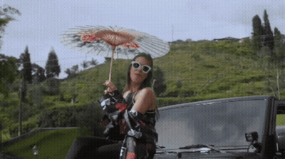 Woman Holding Umbrella Sitting On Car Back GIF