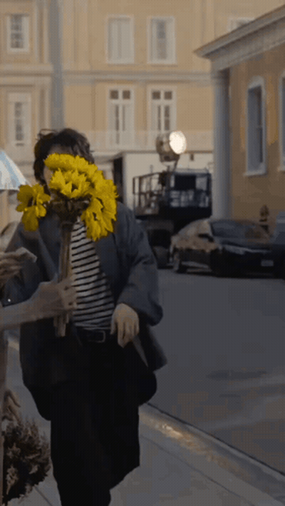 Woman Holding Yellow Flowers Behind Face GIF