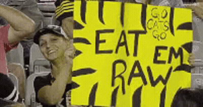 Woman Holding Yellow Sign Saying Eat Em Raw GIF