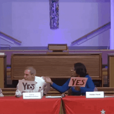Woman Holding Yes Sign In Front Of Man GIF